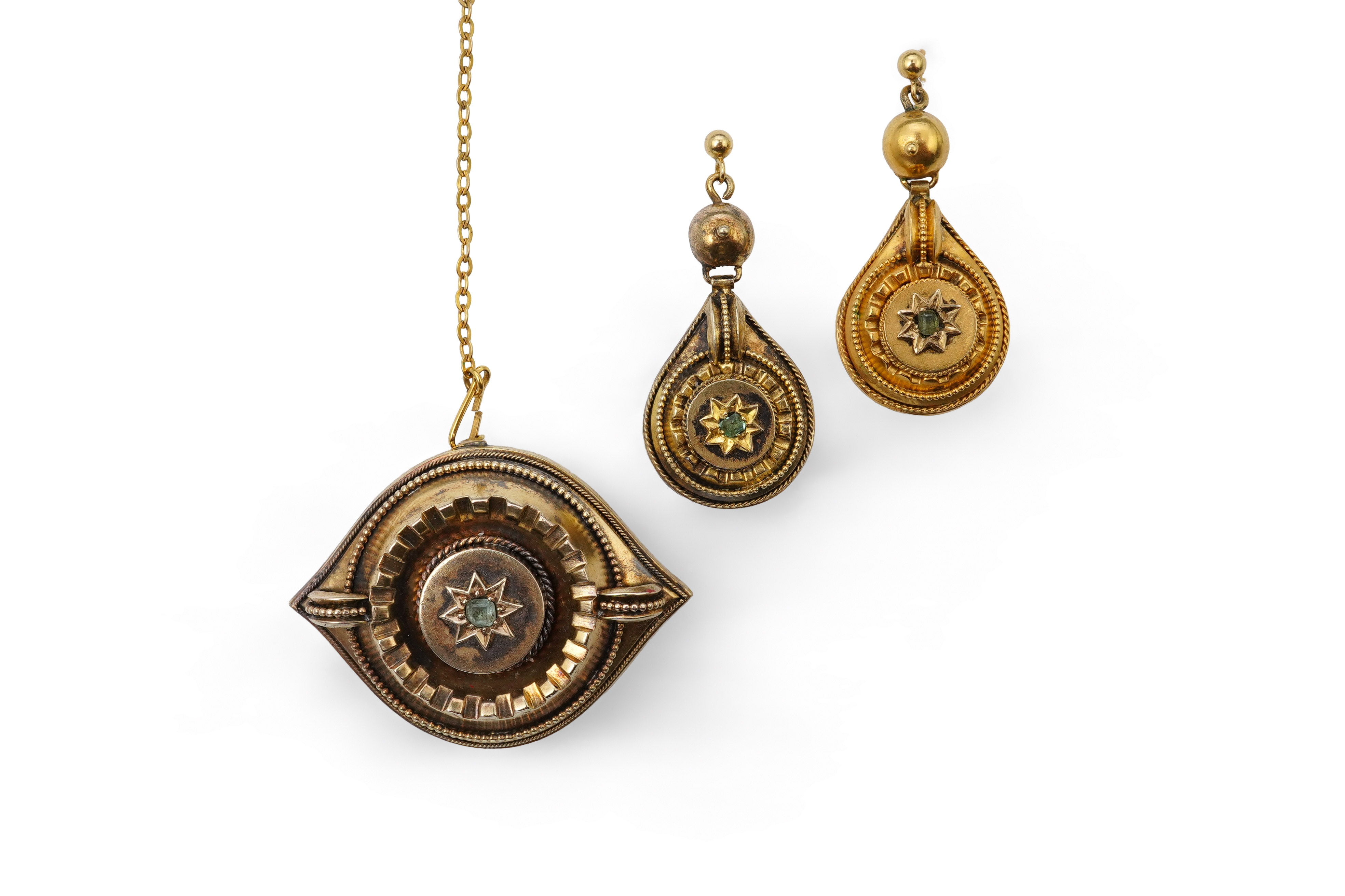 A Victorian gold demi-parure, late 19th century, comprising: a brooch and a pair of earrings, each centring on a circular-cut emerald withing a star border, within mounts accented with stepped and beaded decoration, the